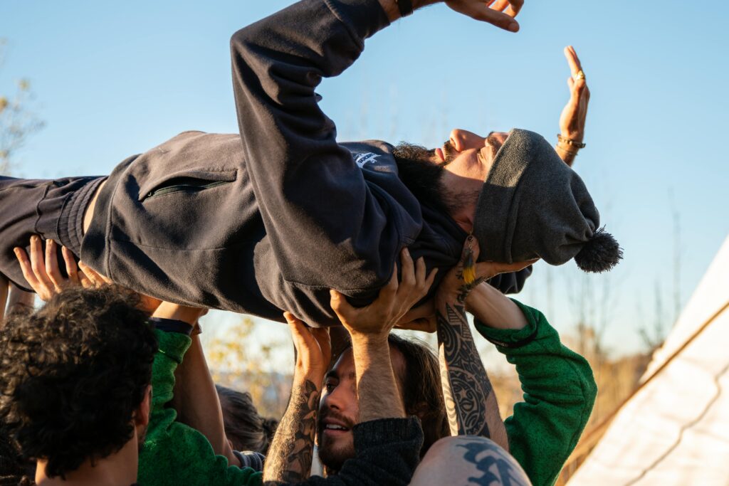 A group of adults lifting a person outdoors, symbolizing teamwork and fun.